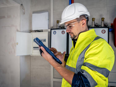 A male technician working on a switchboard with fuses.