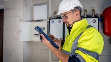 A male technician working on a switchboard with fuses.