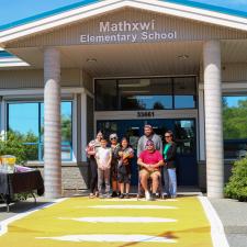 Mathxwí First Nation community members stand in front of school on new orange crosswalk